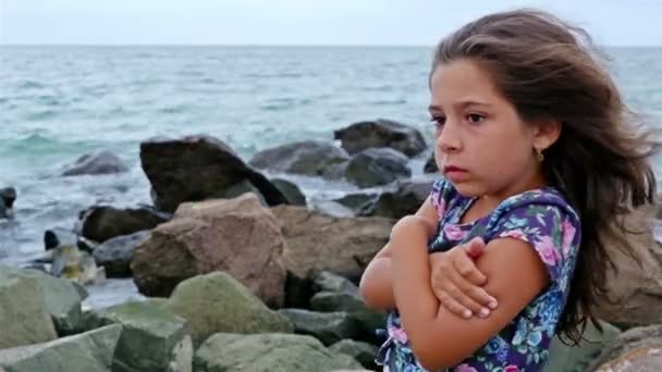 Niña triste parada sola en las rocas junto al mar tormentoso — Vídeos de Stock