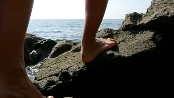 Patas femeninas desnudas pasando por la costa rocosa del mar — Vídeos de Stock