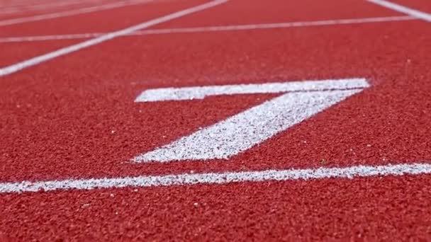 Langzame dolly van een nummer 7 op een atletiekbaan, tegen nummer zeven — Stockvideo