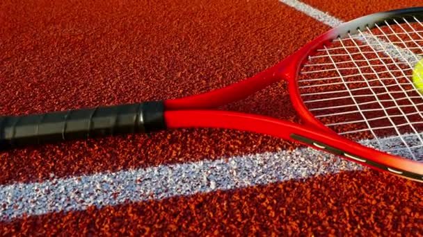 Tennisracket och boll ligger på röda tennisbana, dolly — Stockvideo