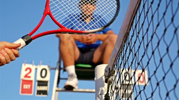 Girl tennis players shake hands over the tennis court net at the end of the match, referee on a seat — Stock Video