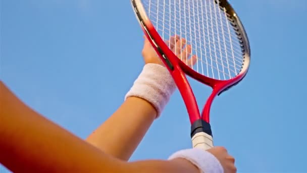 Gros plan de la main d'une joueuse de tennis frappant le filet de sa raquette de tennis contre le ciel bleu — Video