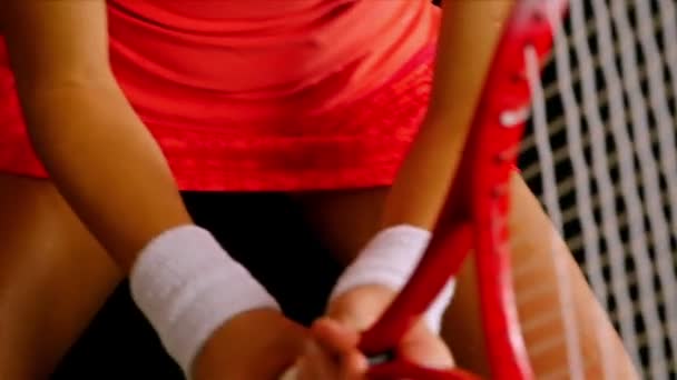Close up da mão de uma jogadora de tênis ajustando a rede de sua raquete de tênis, fundo preto — Vídeo de Stock