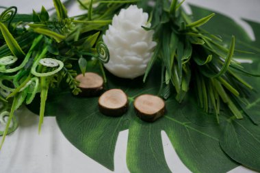 Beyaz koni, mum, yeşil yapraklar ve yapay çimenler.