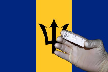 Barbados bayrağının önünde negatif antijenik korona testini gösteren bir el..