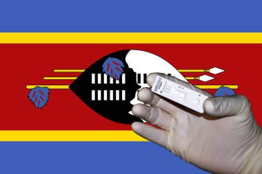 Bir el, Eswatini bayrağının önünde negatif antijenik bir korona testi gösteriyor..