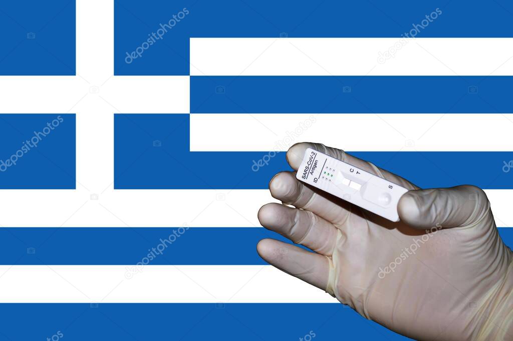 A hand showing a negative antigenic corona rapid test in front of a Flag of Greece