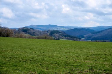 Almanya 'da bulutların, otların ve dağların manzarası, İlkbaharda Rhineland-Palatinate' de Vulkaneifel.
