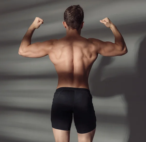 Gros plan du dos musclé du sportif. Bodybuilder montrer biceps — Photo