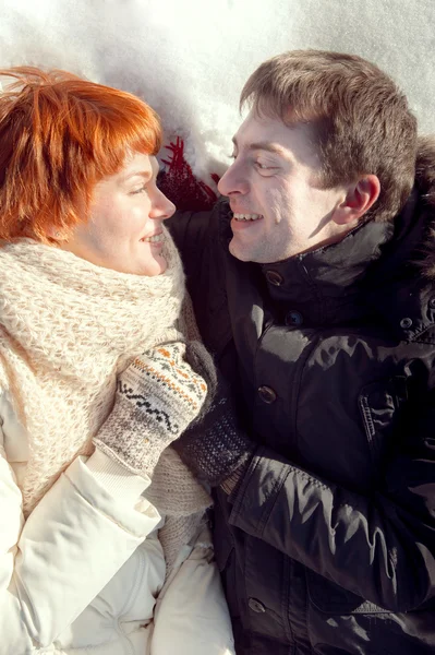 Szczęśliwy uśmiechający się młoda para uścisk na śniegu i patrząc na siebie — Zdjęcie stockowe