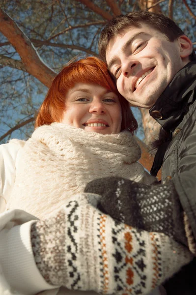 Para patrząc na kamery w winter park pod drzewem — Zdjęcie stockowe