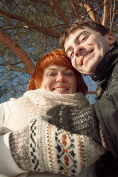 Szczęśliwa para patrząc na kamery w winter park pod drzewem — Zdjęcie stockowe