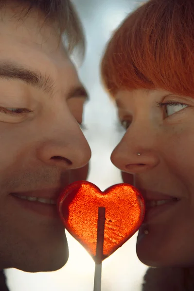 Lyckliga par i kärlek hålla hjärtat formen lollipop — Stockfoto