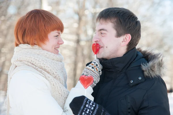 Feliz abrazo de pareja con piruletas en el parque —  Fotos de Stock