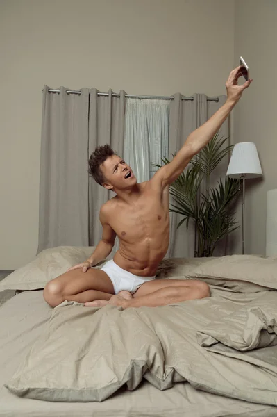 Alkalmas férfi fehérnemű fog selfie az ágyban — Stock Fotó