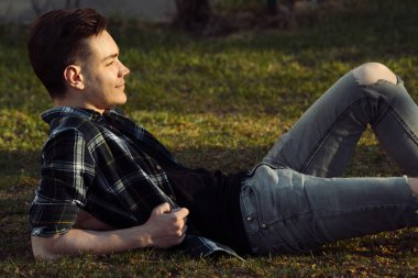 Yakışıklı gülümseyen adam Şehir Parkı çim üzerinde rahatlatıcı