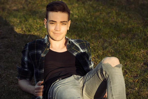 英俊的男人微笑着在城市公园的草地上放松 — 图库照片