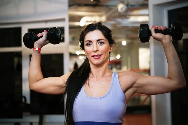 Fit vrouw haar macht met gewicht in sportschool weergeven — Stockfoto