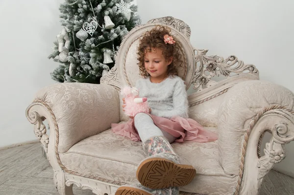 Menina olha para o brinquedo de ovelhas — Fotografia de Stock