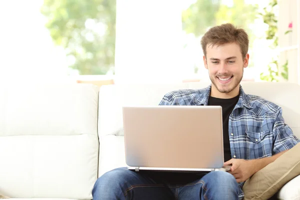 Człowiek za pomocą laptopa siedząc na kanapie w domu — Zdjęcie stockowe
