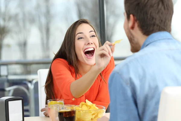 Pareja juguetona comiendo patatas fritas — Foto de Stock