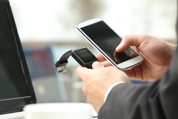 Zakenman een slimme horloge en telefoon synchroniseren — Stockfoto