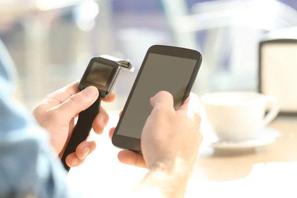 Hombre manos sincronizando un reloj inteligente y teléfono — Foto de Stock