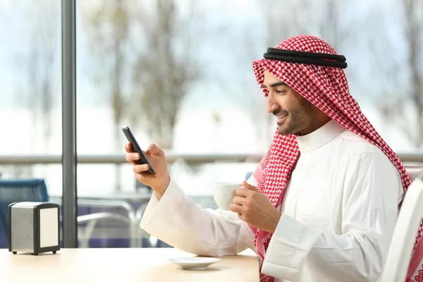 Arabische man texting in een slimme telefoon in een bar — Stockfoto