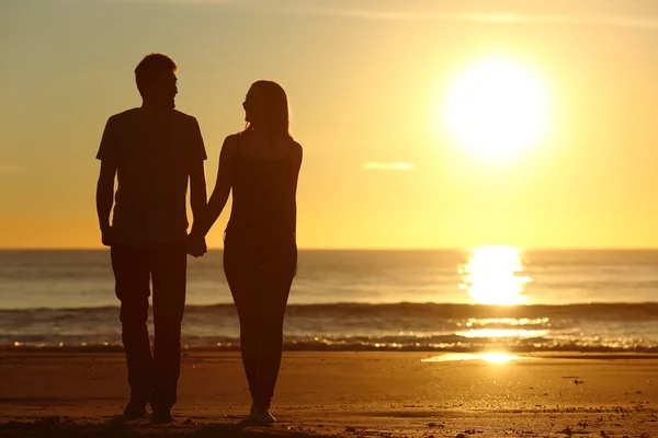 Par siluett promenerar tillsammans på stranden — Stockfoto