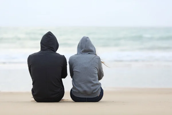 Twee triest tieners zittend op het strand Stockfoto