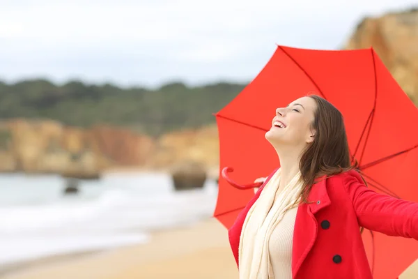 Радісна жінка в червоному збуджена парасолькою — стокове фото