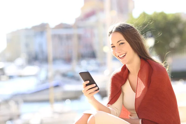 Kobieta za pomocą smart telefonu i patrząc na kamery — Zdjęcie stockowe