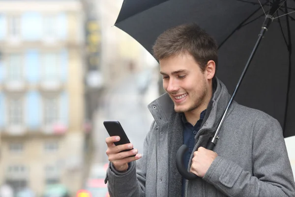 Uomo che usa uno smartphone in un giorno di pioggia — Foto Stock