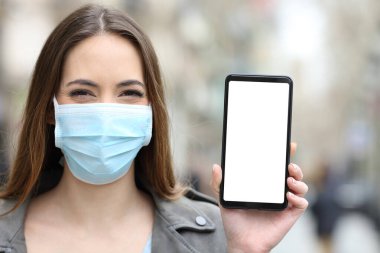 Coronavirus 'u önlemek için maske takan mutlu bir kadının ön manzara portresi ya da boş telefon ekranı gösteren kirlilik.