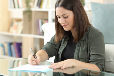 Kontrat imzalayan memnun bir kadın evdeki oturma odasında oturuyor.