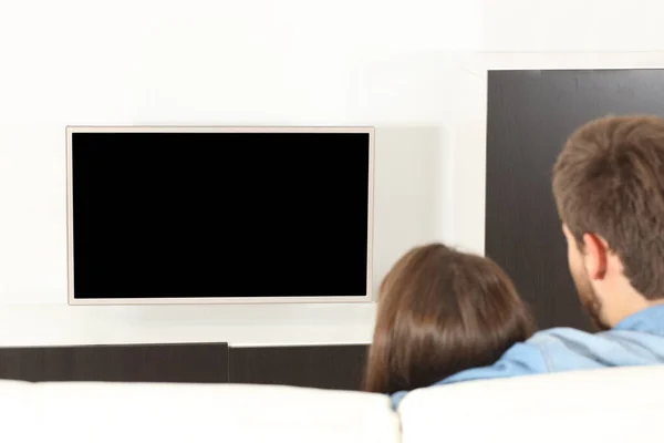 バックビューのカップル抱っこ見ますテレビともに角質スクリーン座っていますザソファに家 — ストック写真