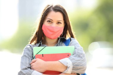 Caddede maske takmış mutlu bir öğrencinin portresi.