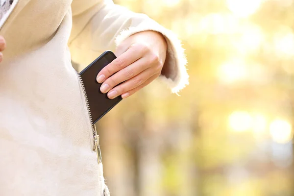 公園で秋のシーズンにジャケットポケットにスマートフォンを保つ女性の手の閉鎖 — ストック写真