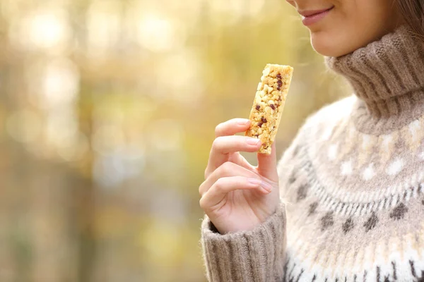 公園で秋に食べる準備ができてシリアルバーを保持している女性の閉じる — ストック写真