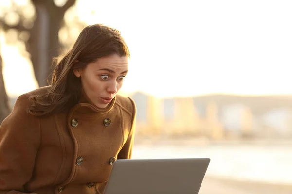 Überraschte Frau Checkt Laptop Winter Strand Bei Sonnenuntergang — Stockfoto