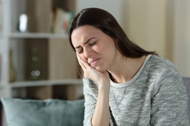 Stresli kadın evdeki kanepede oturup diş ağrısı çekmekten şikayetçi.