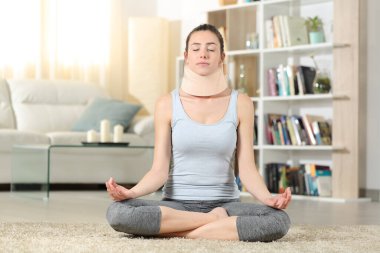 Front view portrait of a disabled woman with neck brace doing yoga exercise at home clipart