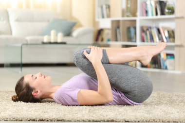 Yoga yapan konsantre bir kadının profili. Evde yerde.
