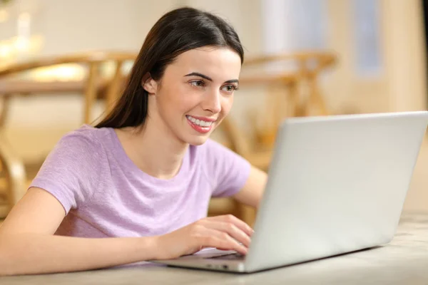 自宅のリビングルームに座ってノートパソコンを使って幸せな女性 — ストック写真