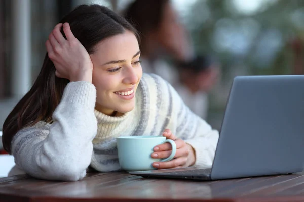 冬にはコーヒーショップに座ってノートパソコンでメディアコンテンツを見て幸せな女性 — ストック写真