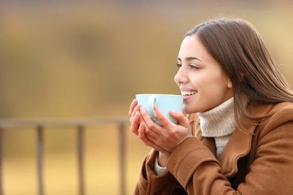 山の冬のテラスで景色を眺めながらコーヒーを飲む幸せな女性 — ストック写真