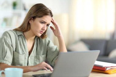 Evde bilgisayardan kötü haber içeriği okuyan hayal kırıklığına uğramış öğrenci.