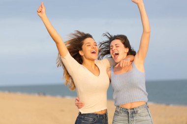 İki heyecanlı arkadaş sahilde birlikte atlayarak tatili kutluyor.