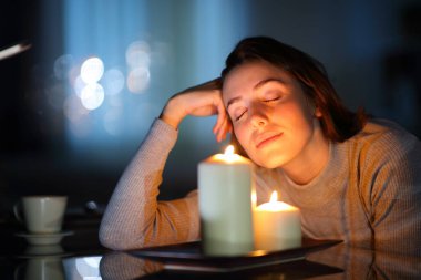 Relaxed woman smelling aromatic candles in the night in the living room at home clipart