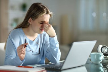 Gözlük tutan bir öğrenci gece geç saatlerde evde bilgisayarla öğreniyor.